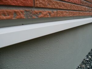 レンガ調タイルに取り付けられた白い水切り金具